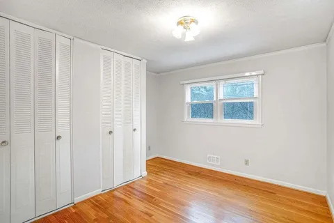 a view of a bedroom with wooden floor and a window