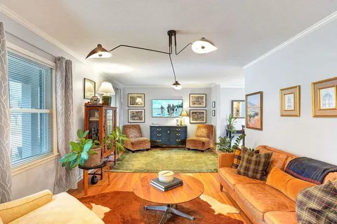 a living room with furniture kitchen view and a large window