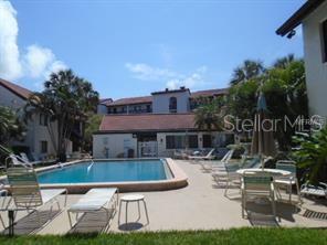 1648 Stickney Point Road, Unit 48202 Sarasota, FL 34231 - Photo 16 of 18 a view of a patio with table and chairs potted plants and palm tree