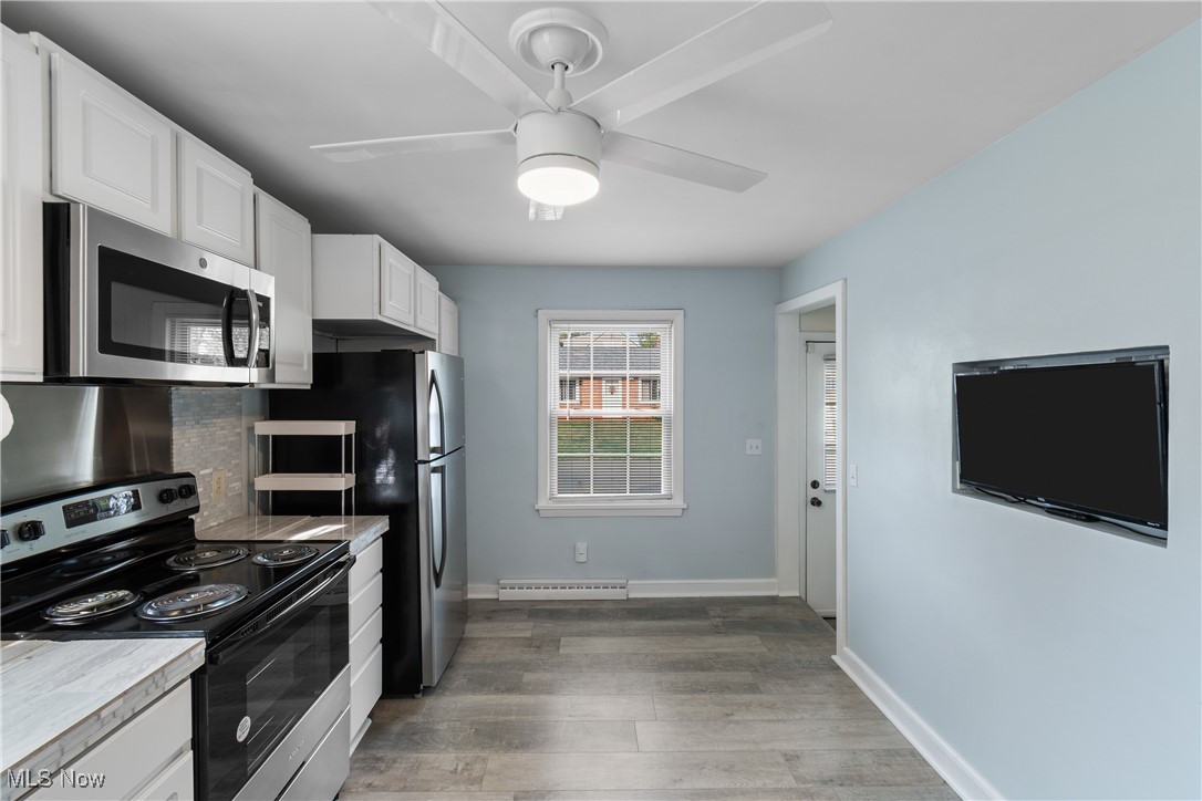 Kitchen with stainless steel appliances, white cabinets, light countertops, light wood-style floors, and ceiling fan