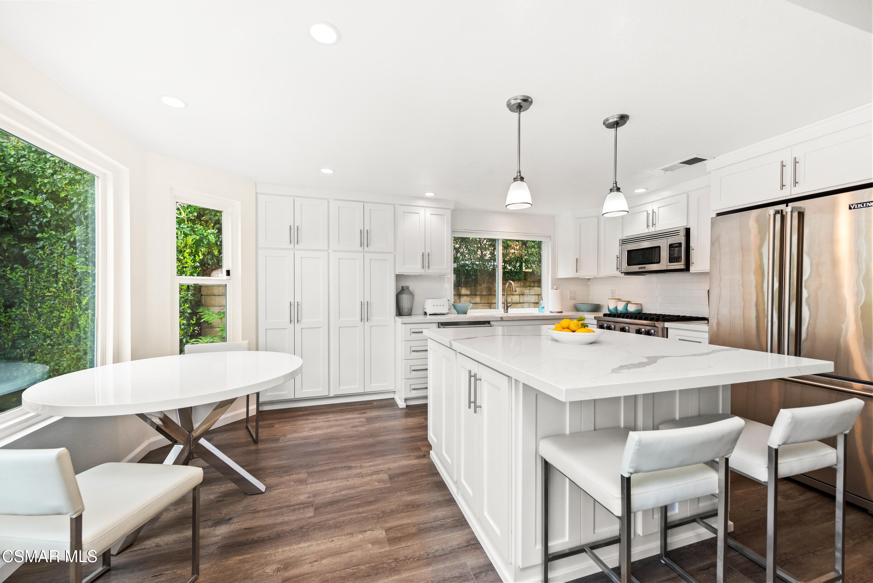 575 Fairfield Road Simi Valley, CA 93065 - Photo 16 of 57 a kitchen with stainless steel appliances a table chairs wooden floors and white walls