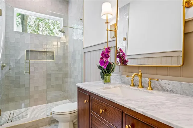 a bathroom with a granite countertop sink a toilet and shower