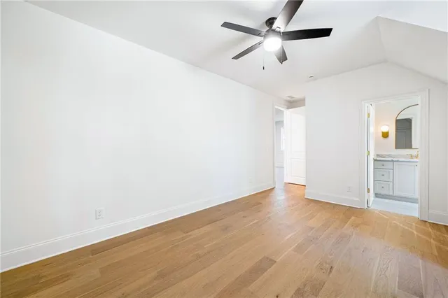 an empty room with wooden floor ceiling fan and windows