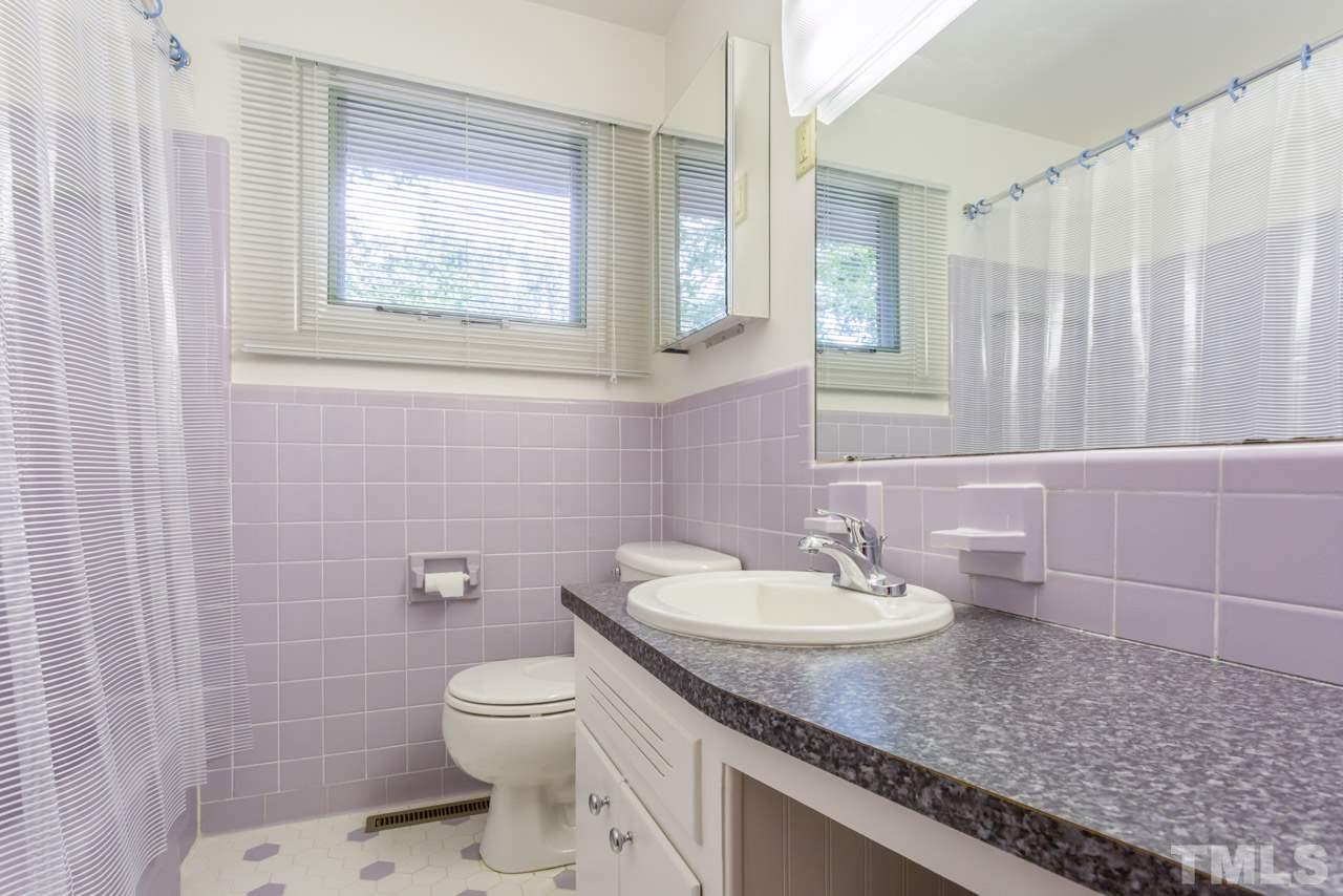 3900 Donna Road Raleigh, NC 27604 - Photo 11 of 25 a bathroom with a granite countertop toilet a sink a mirror and a window