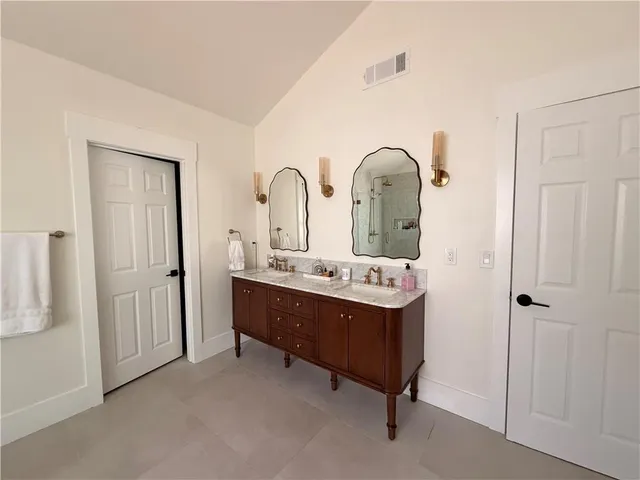 a spacious bathroom with a double vanity sink large mirror and a bathtub