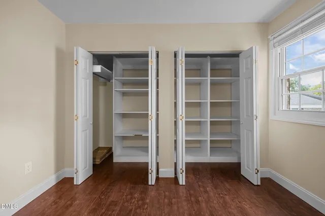 a view of empty room with wooden floor and window