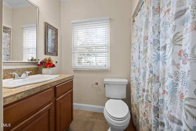 a bathroom with a toilet sink vanity and window