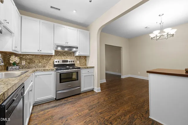 a kitchen with granite countertop white cabinets and stainless steel appliances