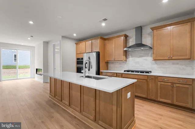 a large kitchen with stainless steel appliances a large counter top a stove a sink and a refrigerator