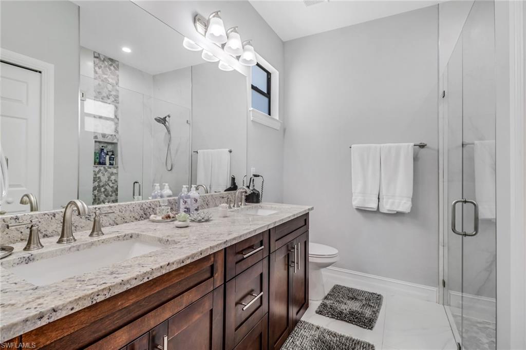 4143 2nd Avenue Northeast Naples, FL 34120 - Photo 9 of 15 a bathroom with a granite countertop sink a toilet and mirror