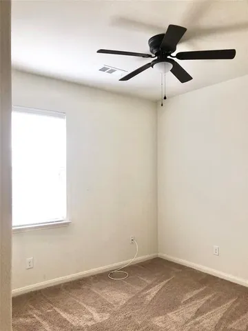 an empty room with a window and a fan