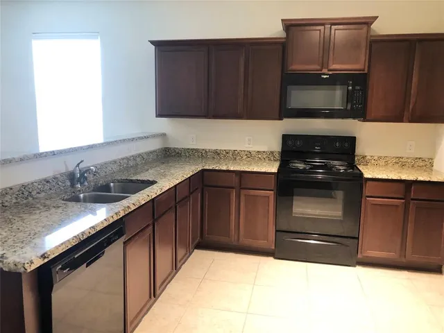 a kitchen with granite countertop a stove a sink and a microwave