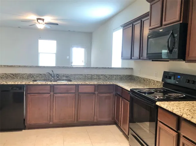 a view of kitchen island with granite countertop a sink