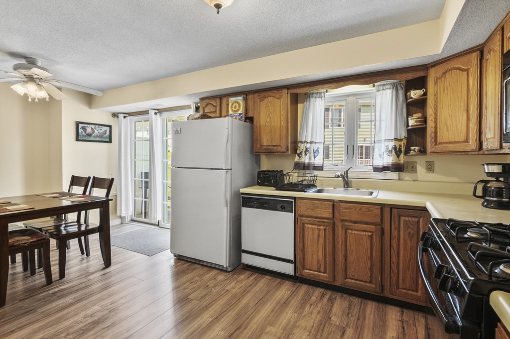 34 Century Way, Unit 34 Gardner, MA 01440 - Photo 9 of 30 a kitchen with granite countertop a refrigerator a sink dishwasher a stove and a dining table with wooden floor