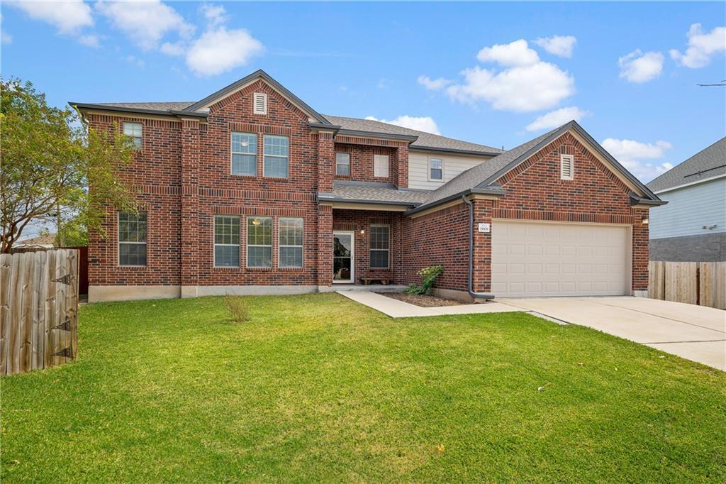 Two-story brick exterior featuring a multi-gable roofline, attached two-car garage, concrete driveway, and front lawn