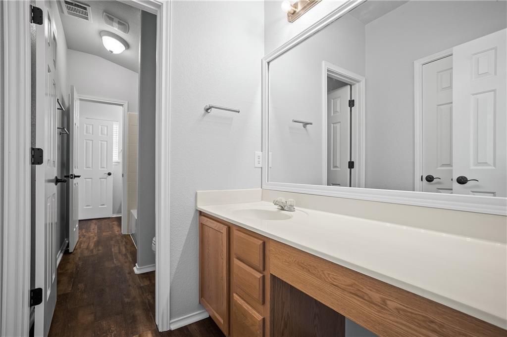 19909 Sap Cove Round Rock, TX 78664 - Photo 13 of 22 Bathroom vanity featuring a light wood-finish cabinet with storage, a large mirror, and an integrated sink with a light-toned countertop
