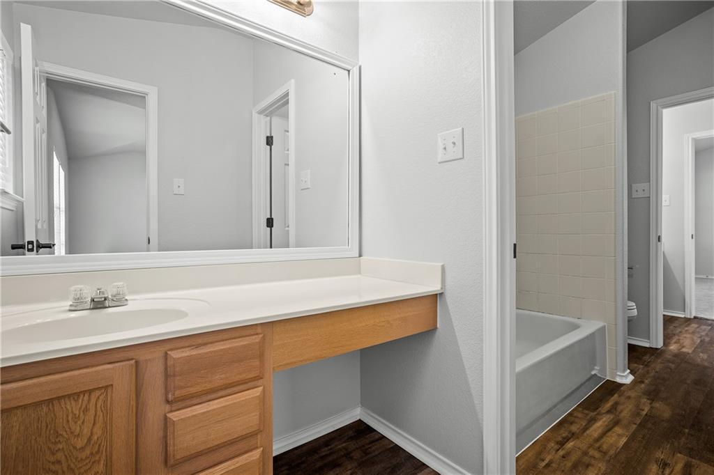 19909 Sap Cove Round Rock, TX 78664 - Photo 14 of 22 Bathroom featuring a single vanity with wood-finish cabinetry, a large integrated mirror, and a white countertop with an undermount sink
