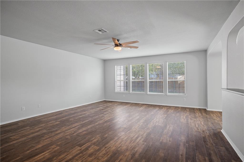 19909 Sap Cove Round Rock, TX 78664 - Photo 15 of 22 Spacious room featuring wood-finish flooring, light gray walls, a ceiling fan with integrated lighting, and a row of three windows with blinds