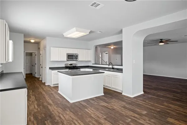 a kitchen with stainless steel appliances kitchen island wooden floors and white cabinets