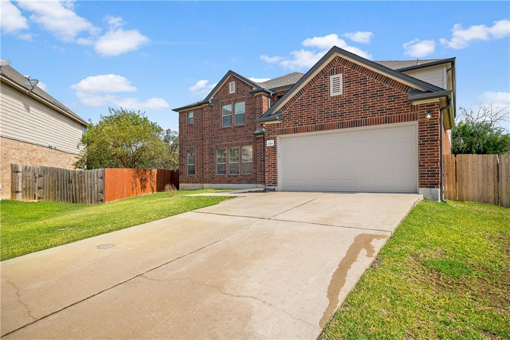 19909 Sap Cove Round Rock, TX 78664 - Photo 2 of 22 Brick exterior with a prominent two-car garage, concrete driveway, and green lawn