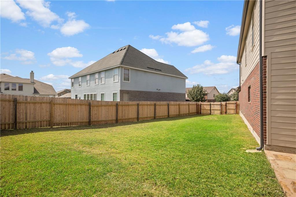 19909 Sap Cove Round Rock, TX 78664 - Photo 22 of 22 Spacious backyard featuring a manicured lawn, full wood privacy fencing, and a side patio with stone pavers