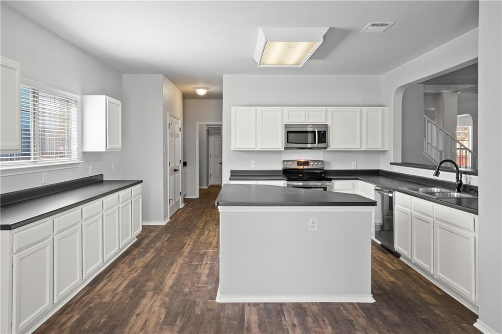 19909 Sap Cove Round Rock, TX 78664 - Photo 8 of 22 Modern kitchen featuring wood-finish flooring, white cabinetry, dark countertops, and stainless steel appliances