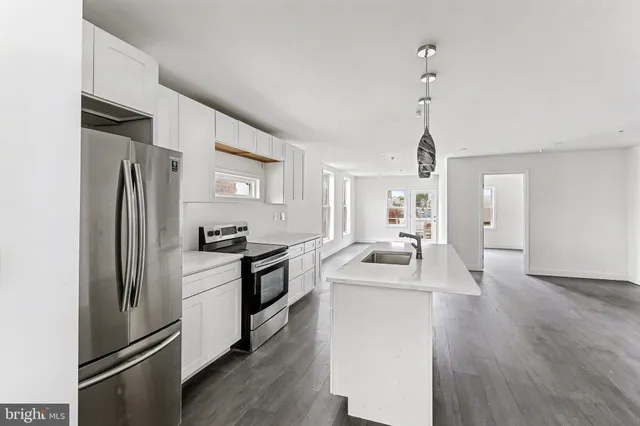 a kitchen with refrigerator a sink and wooden floor