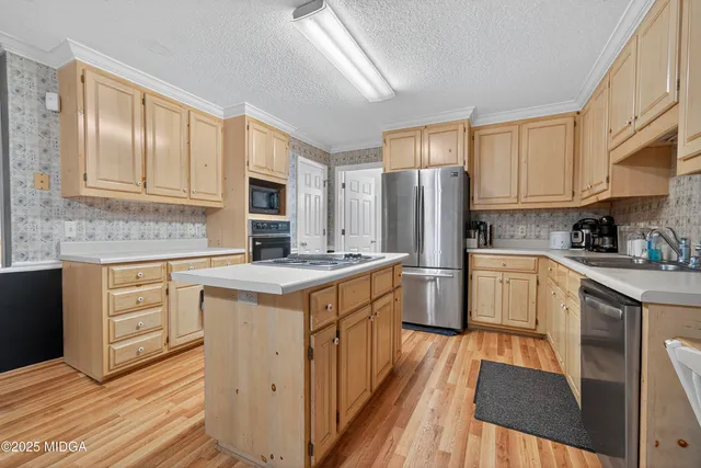 a kitchen with stainless steel appliances granite countertop a stove a sink dishwasher a refrigerator and white cabinets with wooden floor