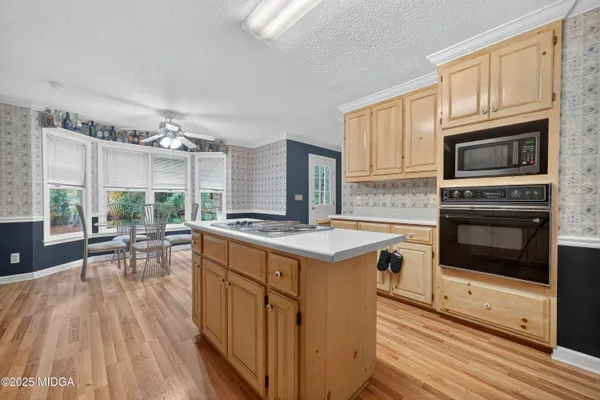 a kitchen with stainless steel appliances granite countertop a stove top oven a sink dishwasher a dining table and chairs with wooden floor