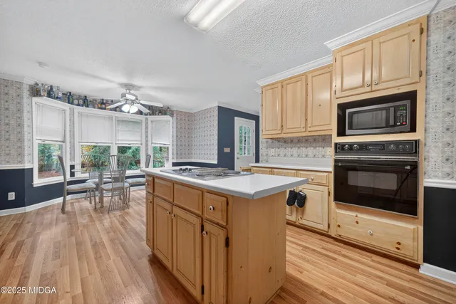 a kitchen with stainless steel appliances granite countertop a stove top oven a sink dishwasher a dining table and chairs with wooden floor