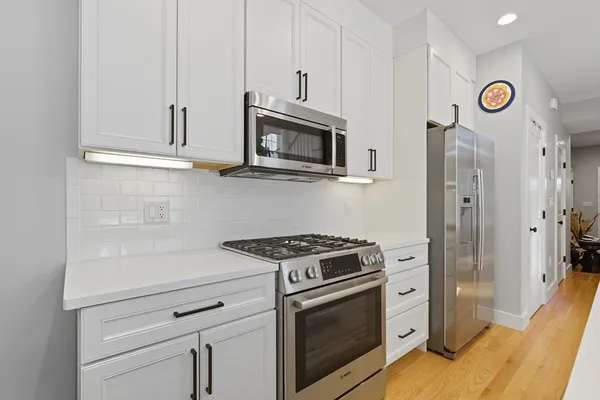a kitchen with stainless steel appliances white cabinets and a stove top oven
