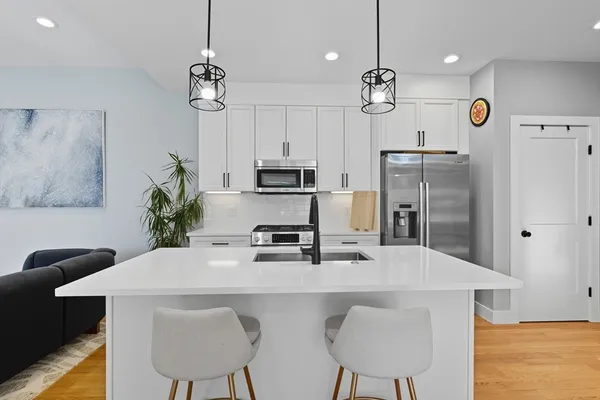 a kitchen with stainless steel appliances a table chairs refrigerator and microwave