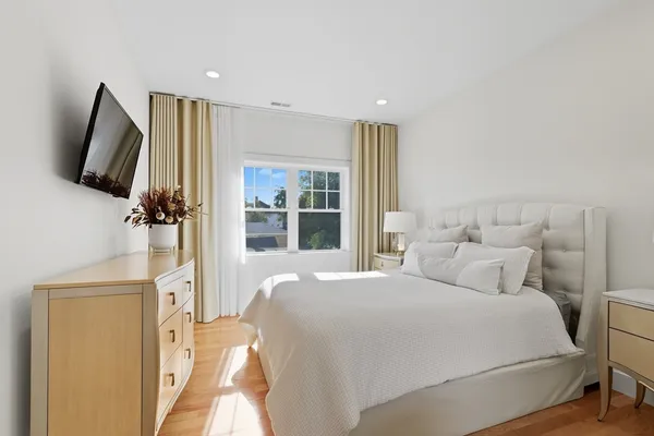 a bedroom with a bed flat screen tv and a large window