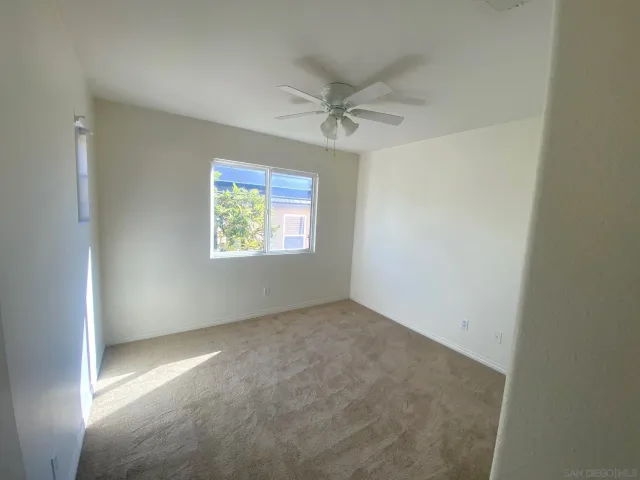 an empty room with windows and fan