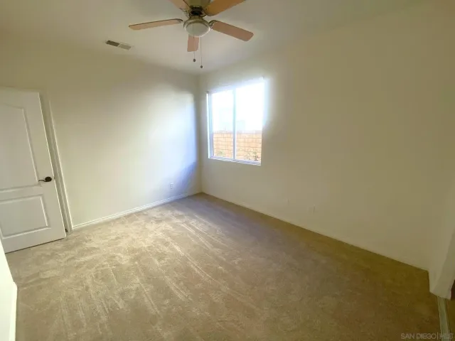 an empty room with a ceiling fan and window