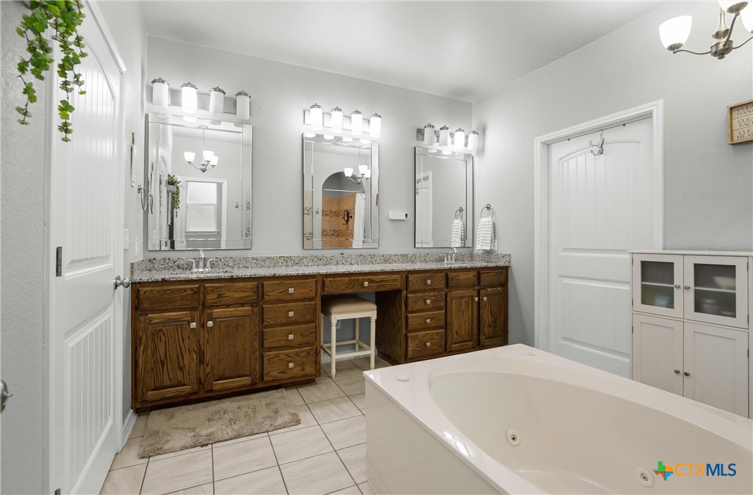 16017 Toby Court Temple, TX 76502 - Photo 15 of 33 a spacious bathroom with a granite countertop tub sink and a mirror