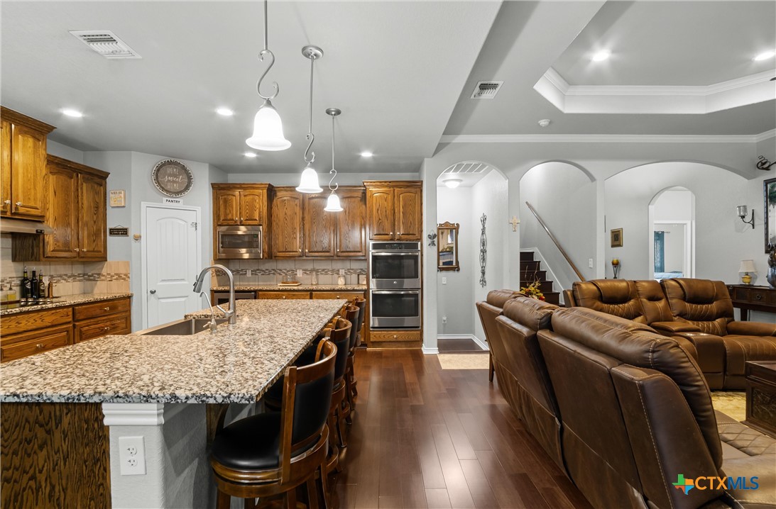 16017 Toby Court Temple, TX 76502 - Photo 7 of 33 a large kitchen with stainless steel appliances kitchen island granite countertop a table chairs in it and wooden floors