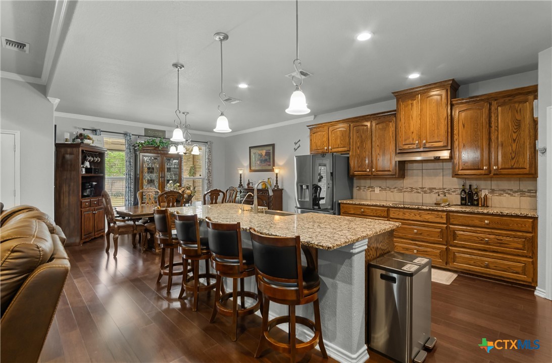 16017 Toby Court Temple, TX 76502 - Photo 8 of 33 a kitchen with stainless steel appliances granite countertop a stove a refrigerator a kitchen island a dining table and chairs with wooden floor