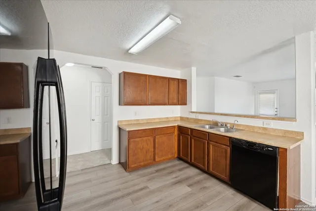 a kitchen with stainless steel appliances granite countertop a refrigerator a sink dishwasher a stove and white countertops with wooden floor