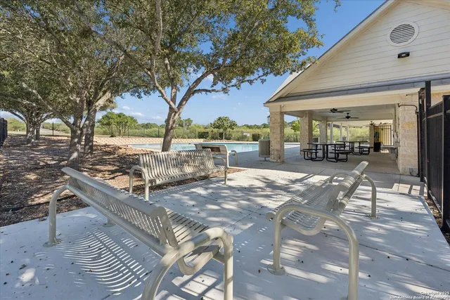 a view of a backyard with table and chairs potted plants and large tree