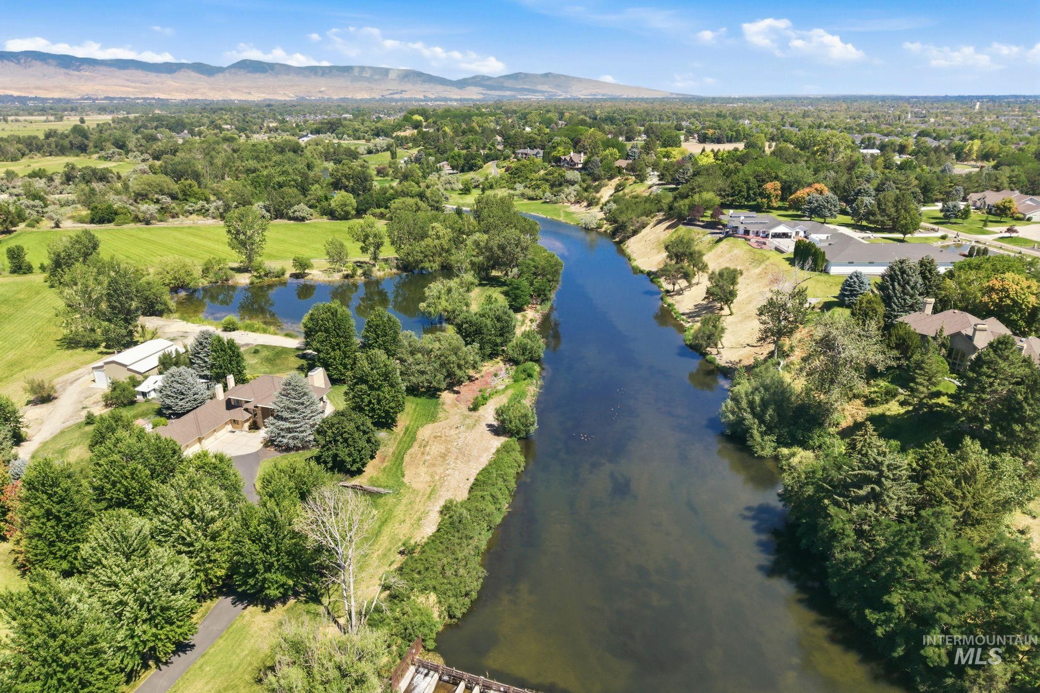 2152 Artesian Road Eagle, ID 83616 - Photo 42 of 50 Expansive aerial view showcasing a significant river, lush green landscaping, a private pond, mature trees, and distant mountains