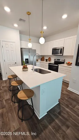 a kitchen with sink a microwave and chairs