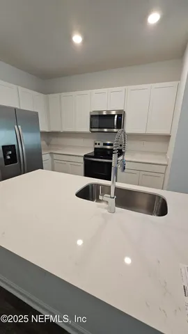 a kitchen with stainless steel appliances a stove a microwave and white cabinets