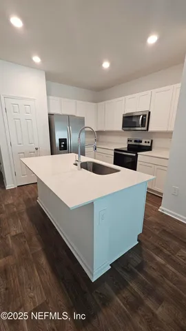 a kitchen with stainless steel appliances a stove top oven a sink dishwasher and a refrigerator with wooden floor