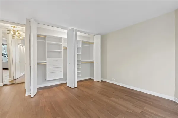 an empty room with wooden floor closet and windows