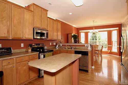 8345 Tie Stone Way Raleigh, NC 27613 - Photo 5 of 12 a kitchen with stainless steel appliances a stove a sink a microwave a dining table and chairs