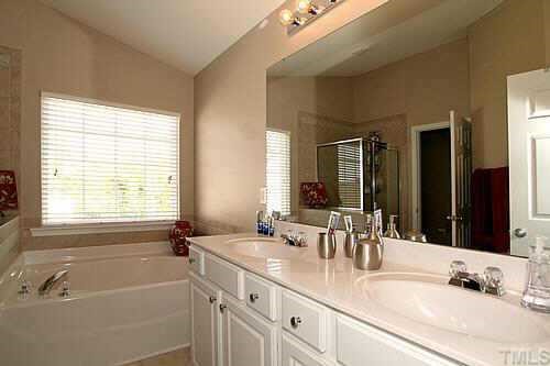 8345 Tie Stone Way Raleigh, NC 27613 - Photo 9 of 12 a bathroom with double vanity sinks a tub and a mirror