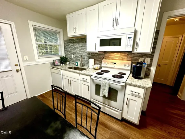 a kitchen with stainless steel appliances a stove a sink a stove a microwave a refrigerator a vanity and a window