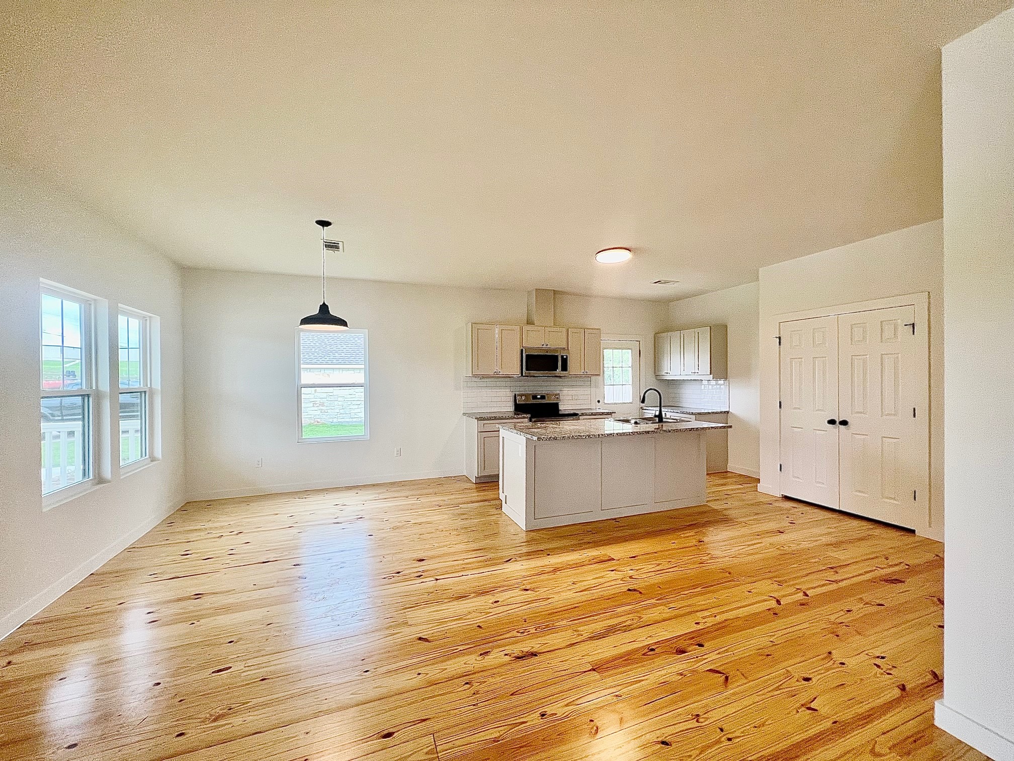 228 North Dixie Street Brenham, TX 77833 - Photo 5 of 10 a large kitchen with kitchen island a sink wooden floor and a refrigerator