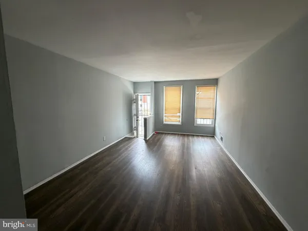 a view of an empty room with wooden floor and window